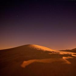 Sand dune after sunset against starry sky
