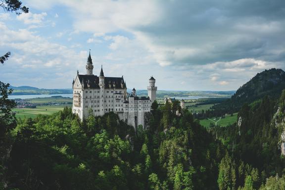Majestic white castle on hill amidst thick forest trees