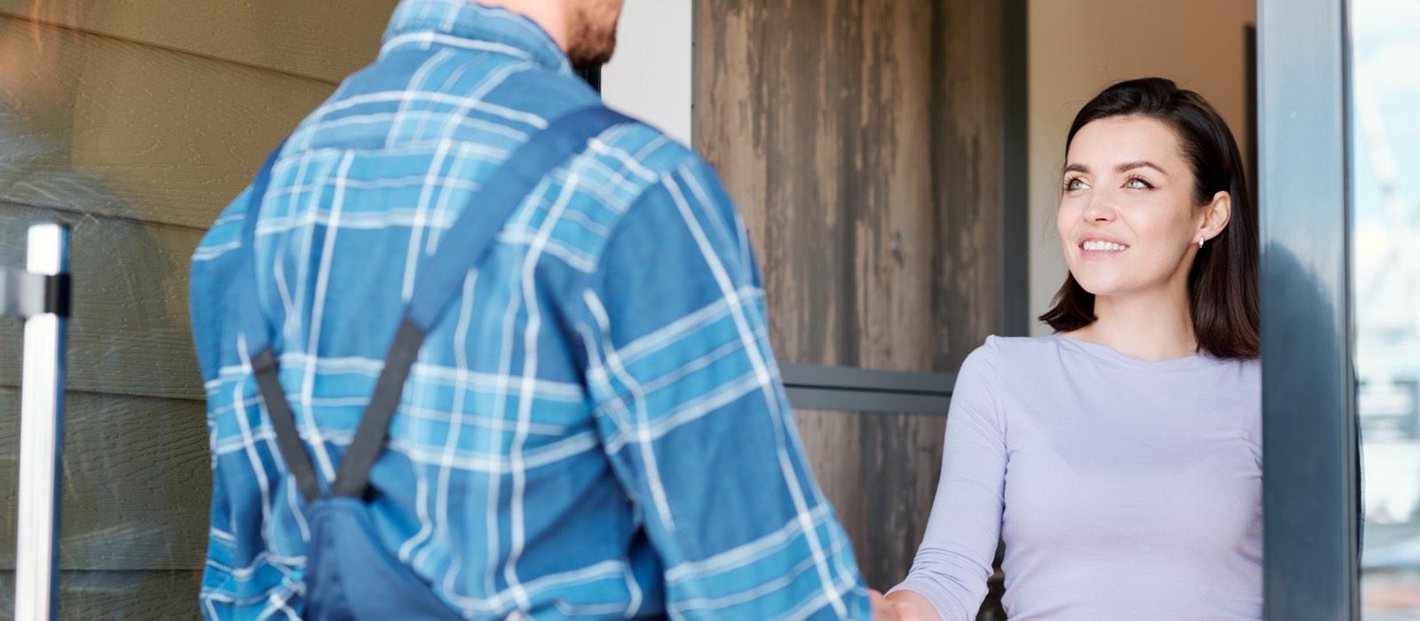 Smiling woman shakes hand of service technican